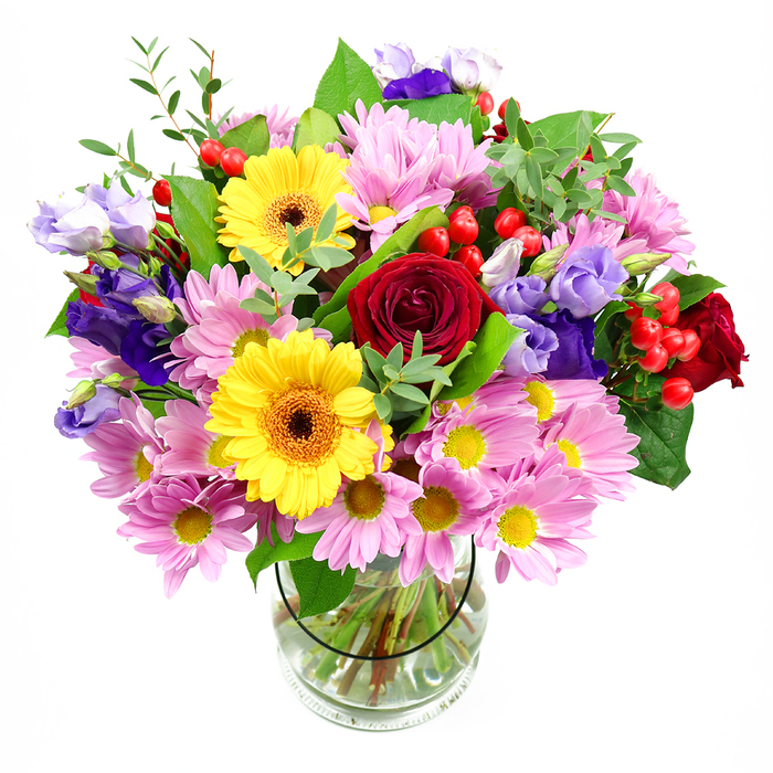 Set against a pristine white background, this lush floral arrangement in a clear glass vase feels like a concentrated burst of garden life brought indoors. At its core, velvety red roses form a rich, romantic heart to the design, their deep tones adding depth and a sense of classic elegance. Flanking them, two radiant yellow gerbera daisies with dark brown-orange centres shine brightly, their daisy-like faces lending a mood of optimism and joy. Around these focal blooms, generous clusters of pink and lilac daisies or chrysanthemums spill outward, each flower with a tiny yellow centre, building a soft, cushiony layer that makes the bouquet look full and welcoming. Threaded gracefully through this pastel cloud are stems of purple and lavender lisianthus, their bell-shaped blossoms and slightly twisted buds creating gentle curves and cooler accents of colour. Here and there, glossy red hypericum berries emerge between petals and foliage, adding a different texture and a small spark of contemporary style. The arrangement is framed with varied greenery-broad, reassuringly solid leaves and finer, more delicate sprigs-that give structure and a sense of movement, reminiscent of the layered planting in the green spaces around Finsbury Park. The glass vase itself is simple and cylindrical, allowing the viewer to see the parallel lines of the trimmed stems and the clarity of the water, a quiet testament to the florist's attention to detail. Lit with clean, even light, the bouquet looks ready to brighten a kitchen table on Seven Sisters Road or to greet guests in a hallway just off Stroud Green Road, perfect for birthdays, thank you gestures, or sending warm wishes across North London.
